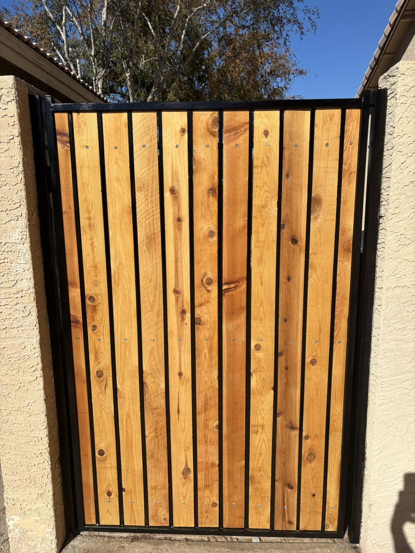 Gate after refurbishment with clear-sealed natural cedar slats and freshly painted black frame