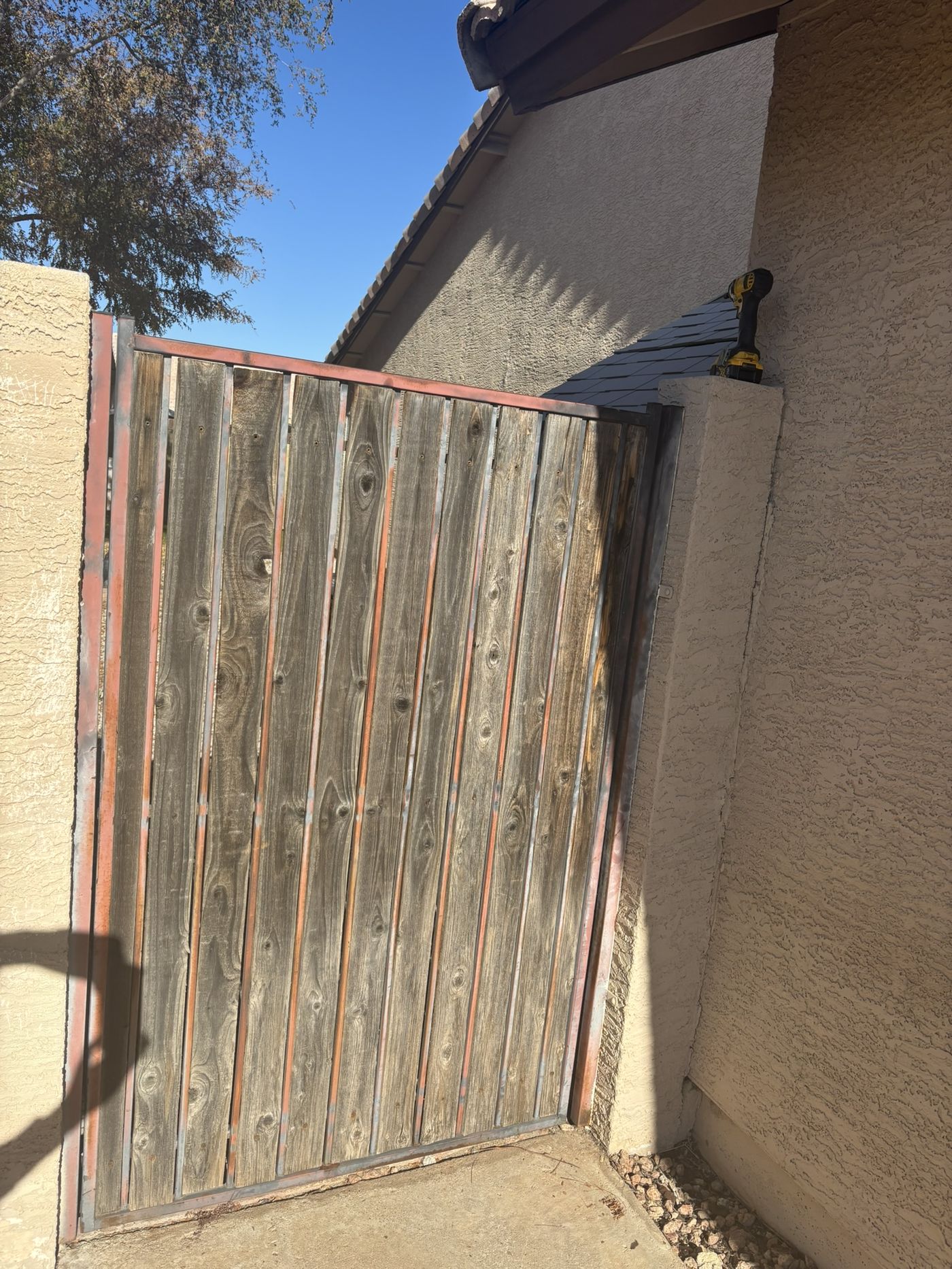 Gate with faded grey wood slats and rusting frame before refurbishment